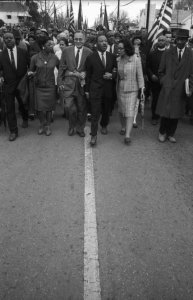 Selma to Montgomery March 1965 Day 5, Triumphant civil rights leaders entering Montgomery on Oak Street. From left to right: Ralph and Juanita Abernathy, Ralph Bunche, Dr. Martin Luther King, Jr. and Coretta Scott King with Frederick Reese. Price on request.